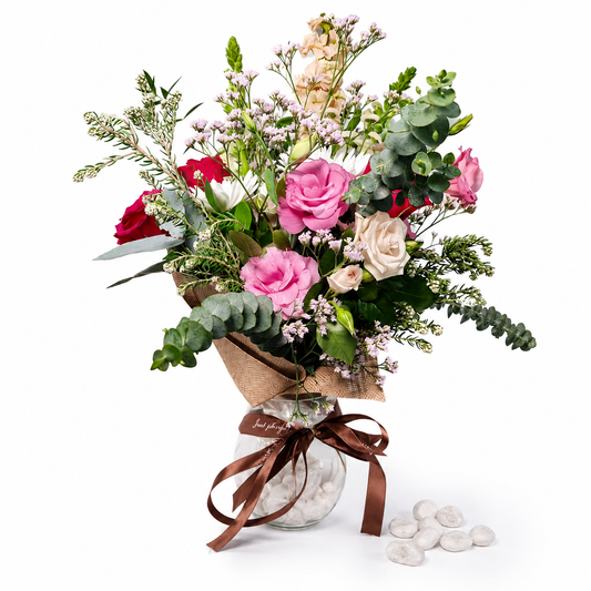 Close-up of pink roses and white flowers with greenery in a glass vase