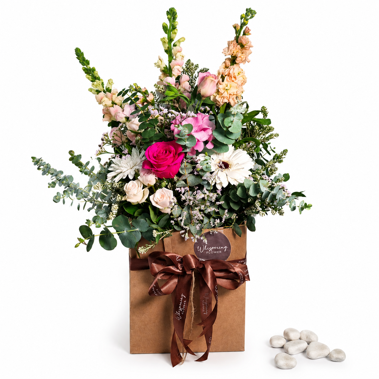 Close-up of a bright bouquet with roses, gerbera and snapdragons in a kraft paper gift bag.