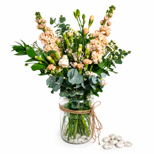 Soft peach and pink bouquet of stocks and carnations with eucalyptus in a clear glass vase
